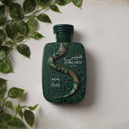 Rasasi Hawas Boa Eau de Parfum bottle displayed on a light marble surface beside trailing green leaves